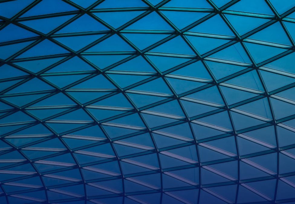 Geometric glass roof with triangular grid pattern in blue gradient light.